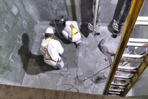 men cutting fiberglass panels in a sump pit
