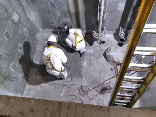 men cutting fiberglass panels in a sump pit